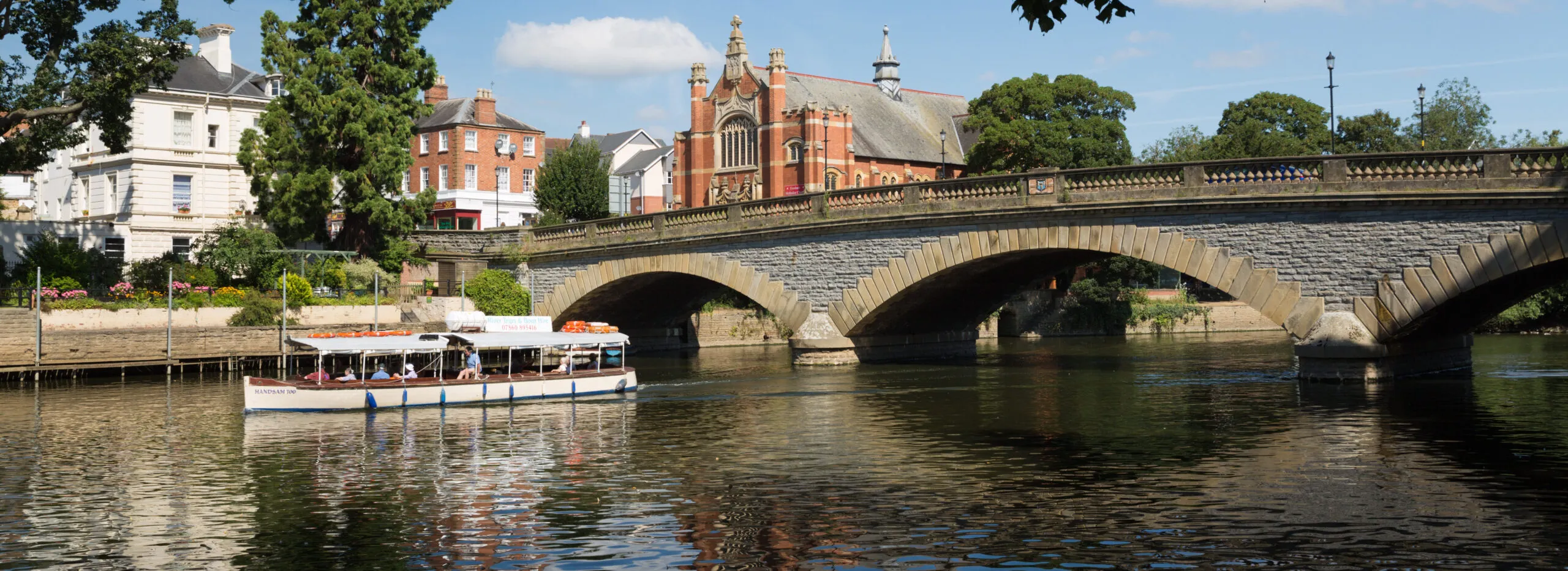 A pleasure boat on the River Avon passing under the bridge in Evesham, Worcestershire