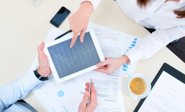 Two people reviewing business data together on a tablet